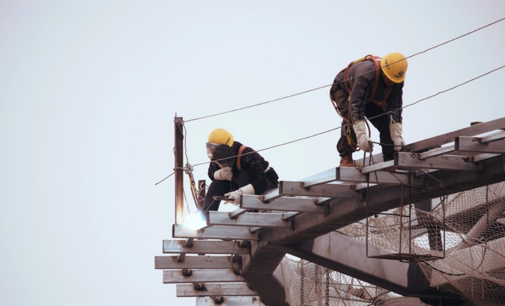 Construction workers welding on metal roof