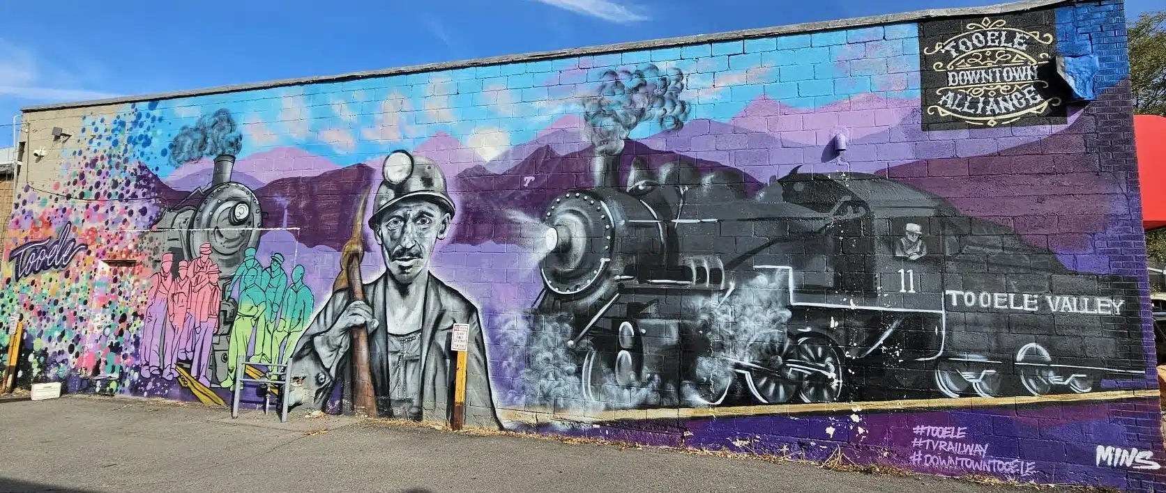 A building in Tooele UT with a mural painting of a train and construction workers