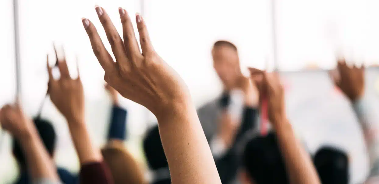 hands raised in a meeting asking questions