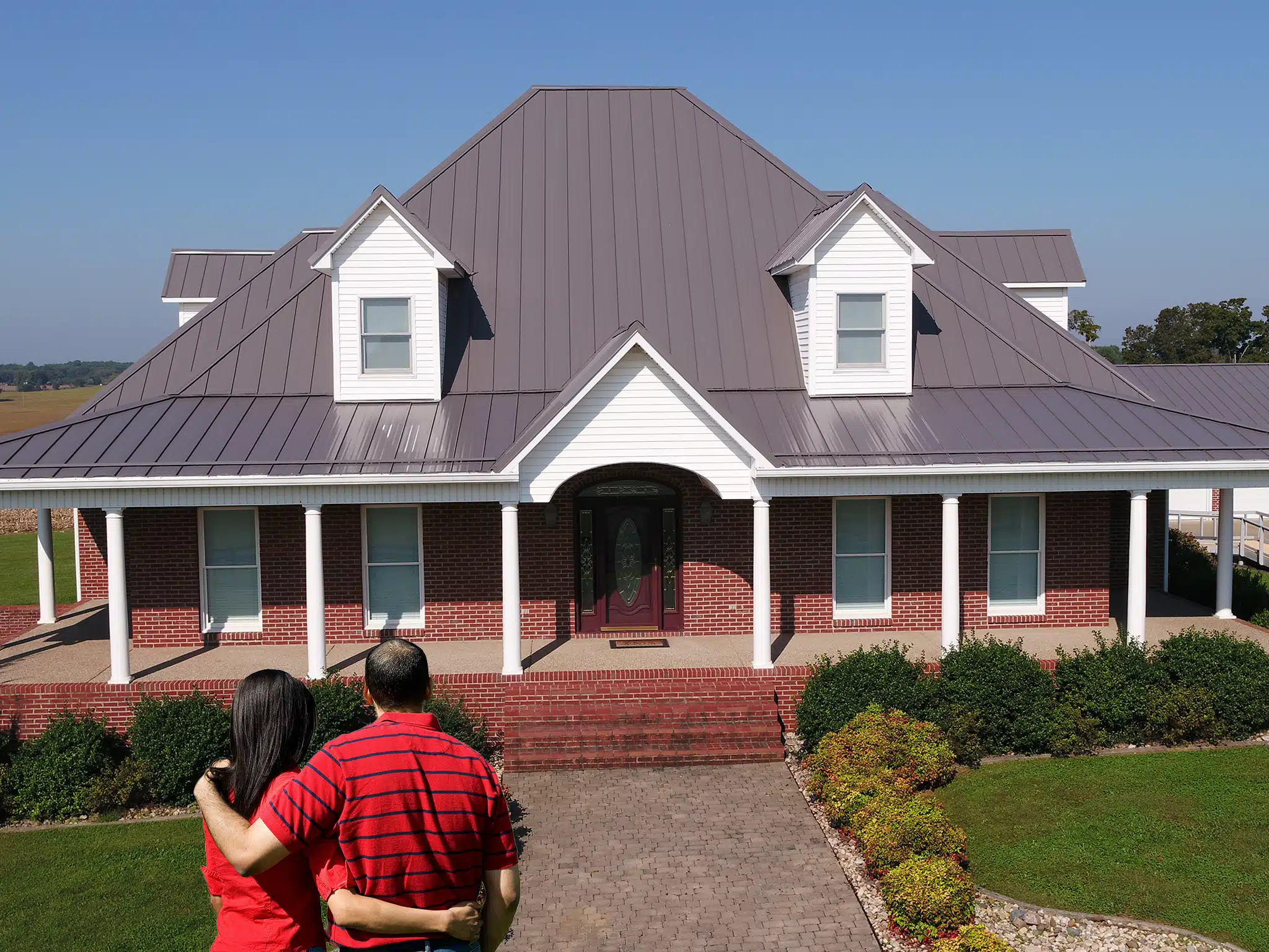 Couple standing in front of a home with a charcoal Horizon-Loc metal roof
