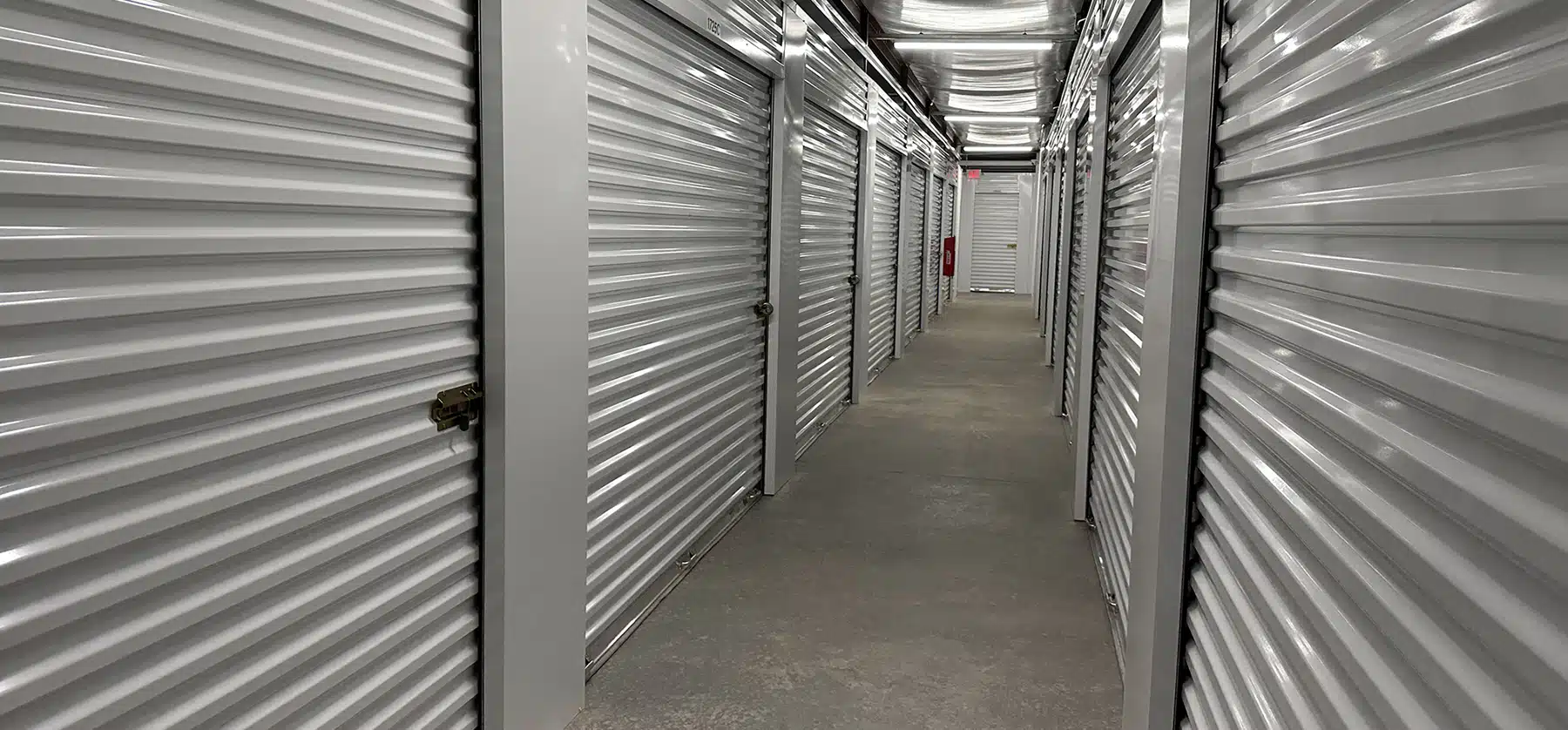 Row of white roll up doors inside of a self-storage facility